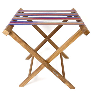 Folding wooden teak luggage rack with blue, lavender and burgundy multi stripe cotton webbing straps for hotel guest room