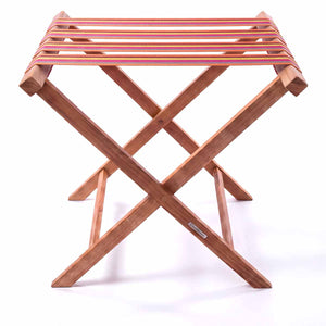 Folding wooden teak luggage rack with pink, yellow and terracotta stripe cotton webbing straps for hotel guest room