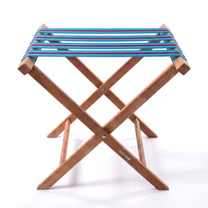 Folding wooden teak luggage rack with turquoise blue, navy, pink and white stripe cotton webbing straps for hotel guest room