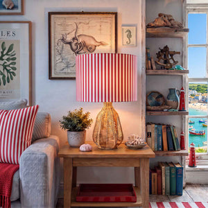 A red and white vertically striped fabric lampshade styled in a nautical-themed living room. with red accents