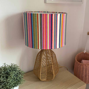 A striped fabric lamp shade with colourful pretty vertical stripes on a lamp