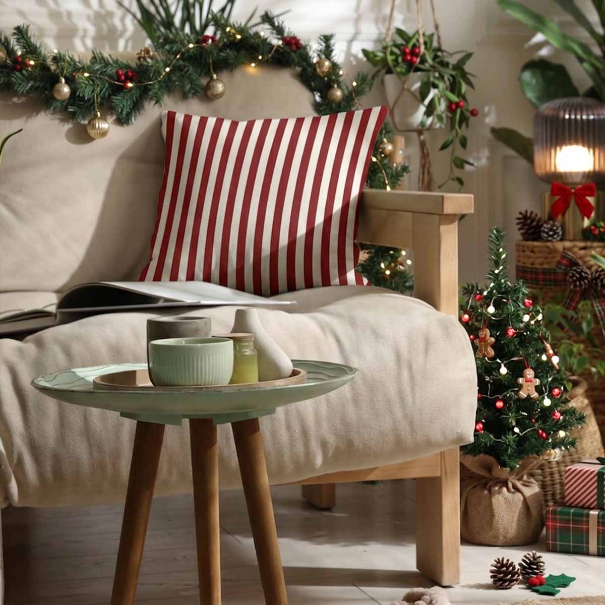 A cozy christmas living room scene with a burgundy-and-white striped cushion on a sofa
