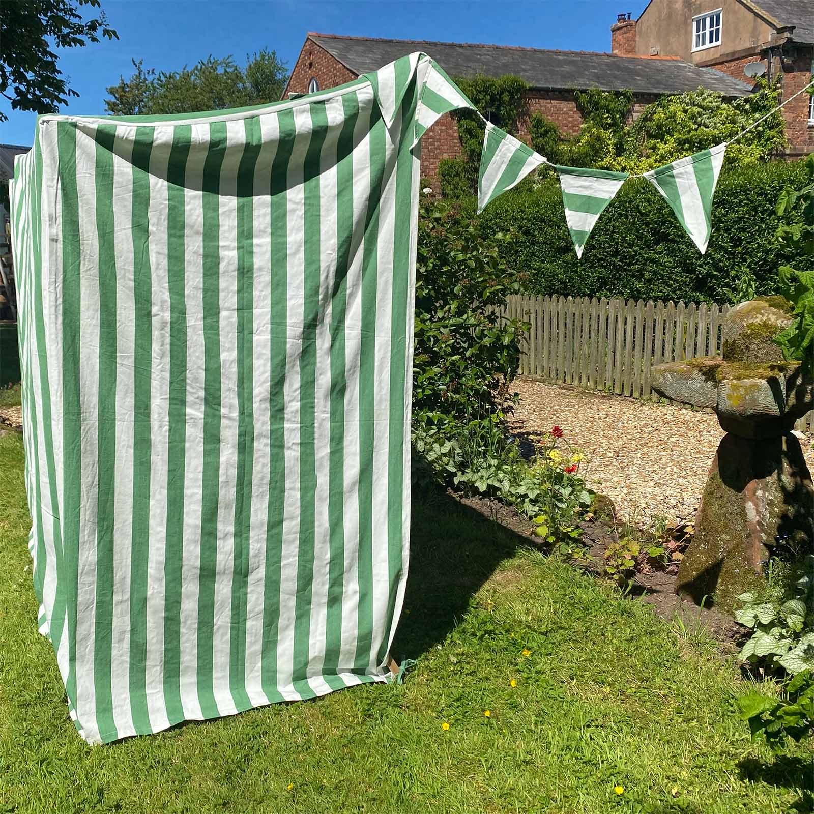 Green and white striped canopy set up in a garden with bunting