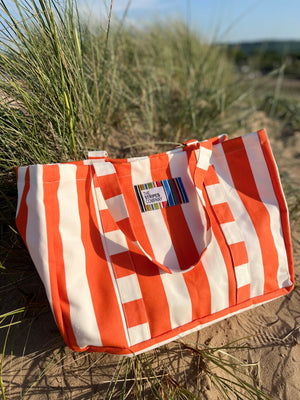 Orange and white striped bag on beach sand dunes