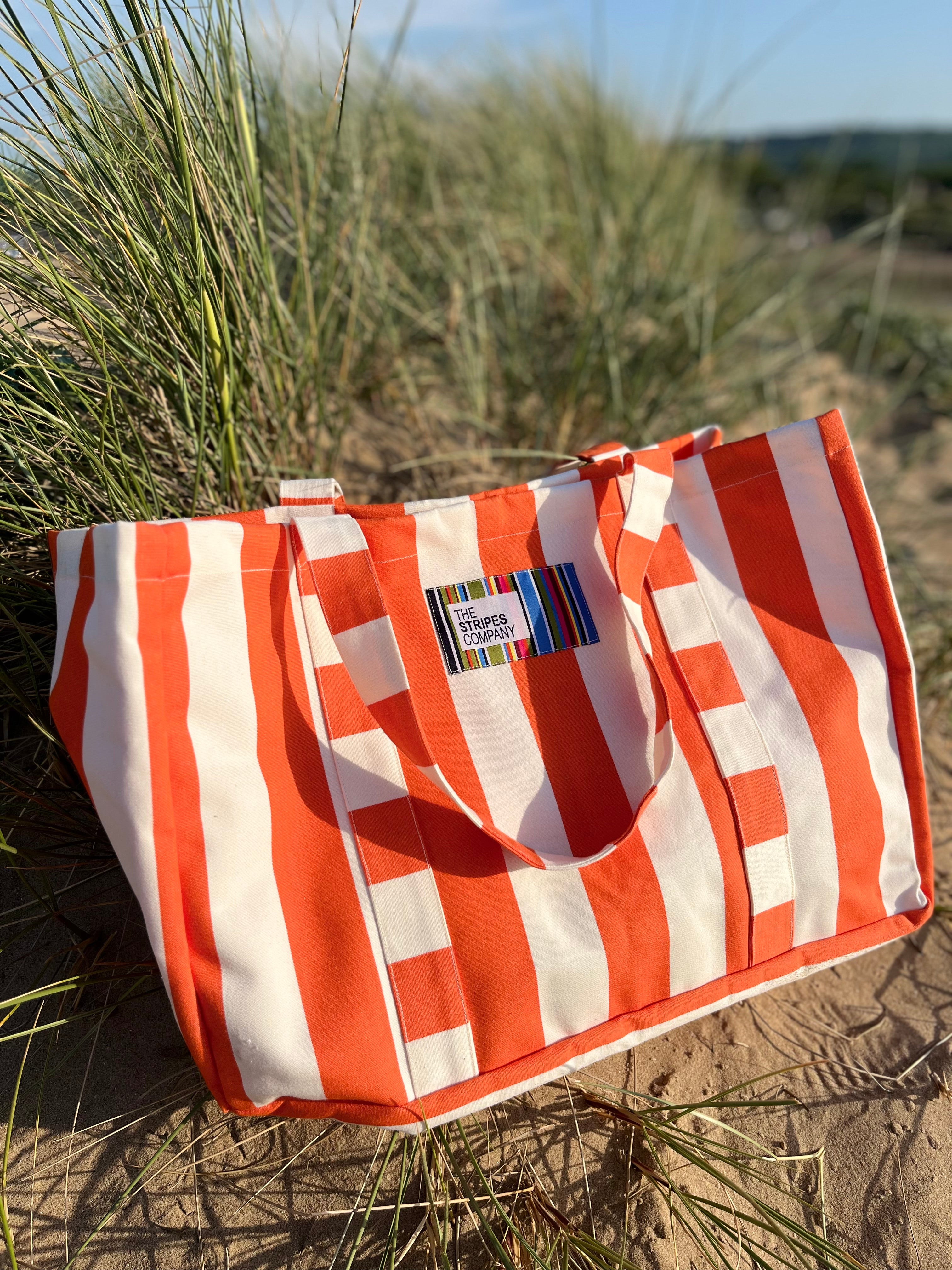 Orange and white striped bag on beach sand dunes