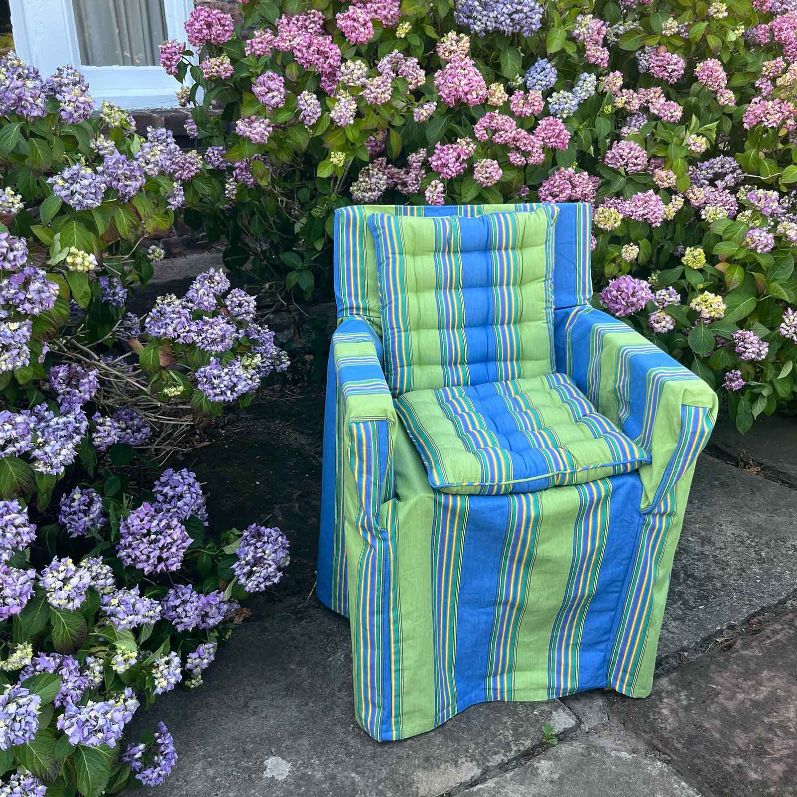 blue and green striped pattern seat pads on a slipcovered outdoor armchair 