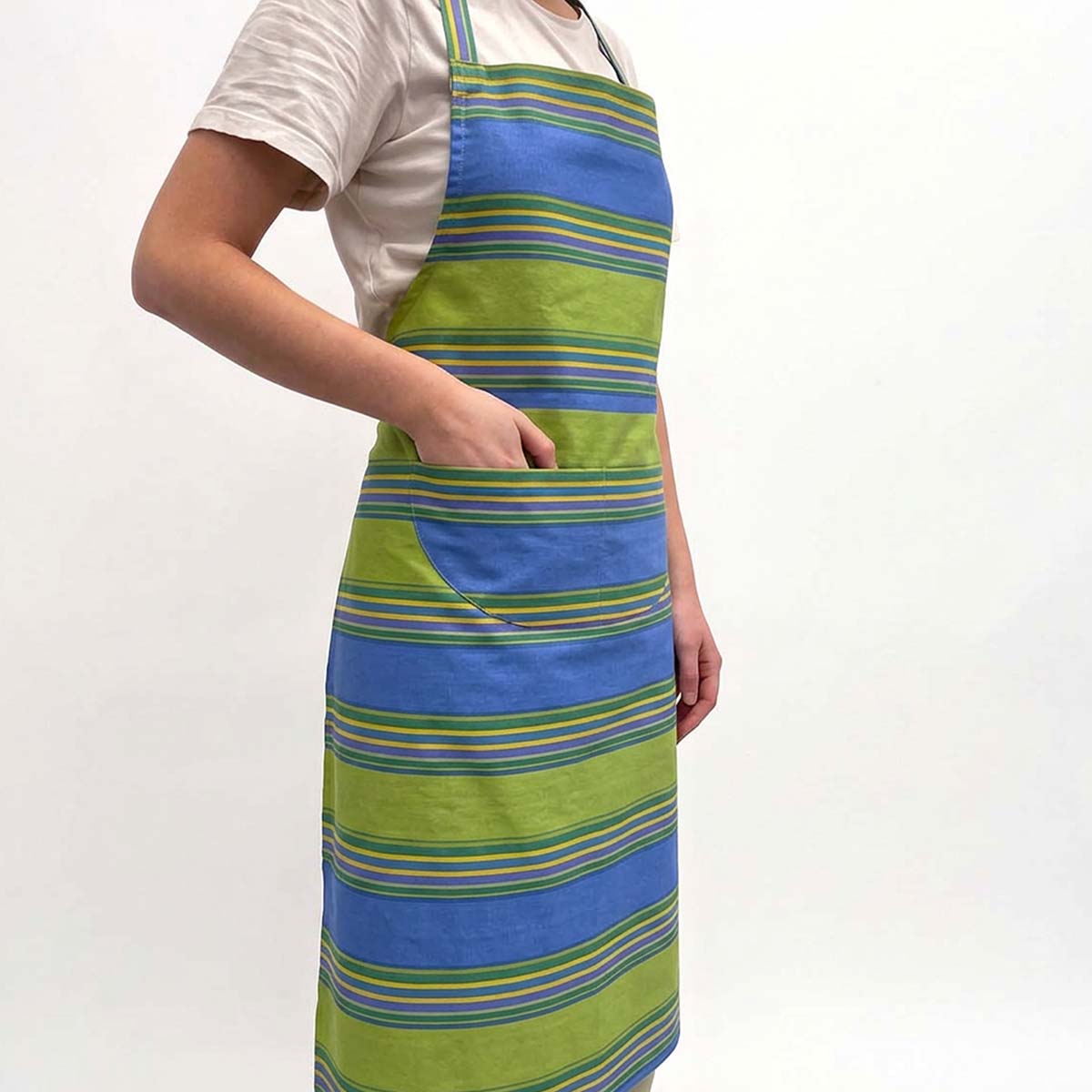 A person wearing a striped apron with blue and green horizontal bands, featuring a large front pocket