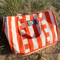 orange and white striped bag - the stripes company brand on a sandy beach