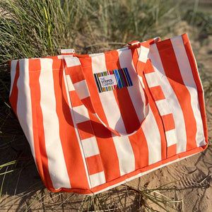 orange and white striped bag - the stripes company brand on a sandy beach