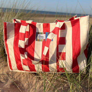 Red and white striped bag with the stripes company brand label on a sandy beach.