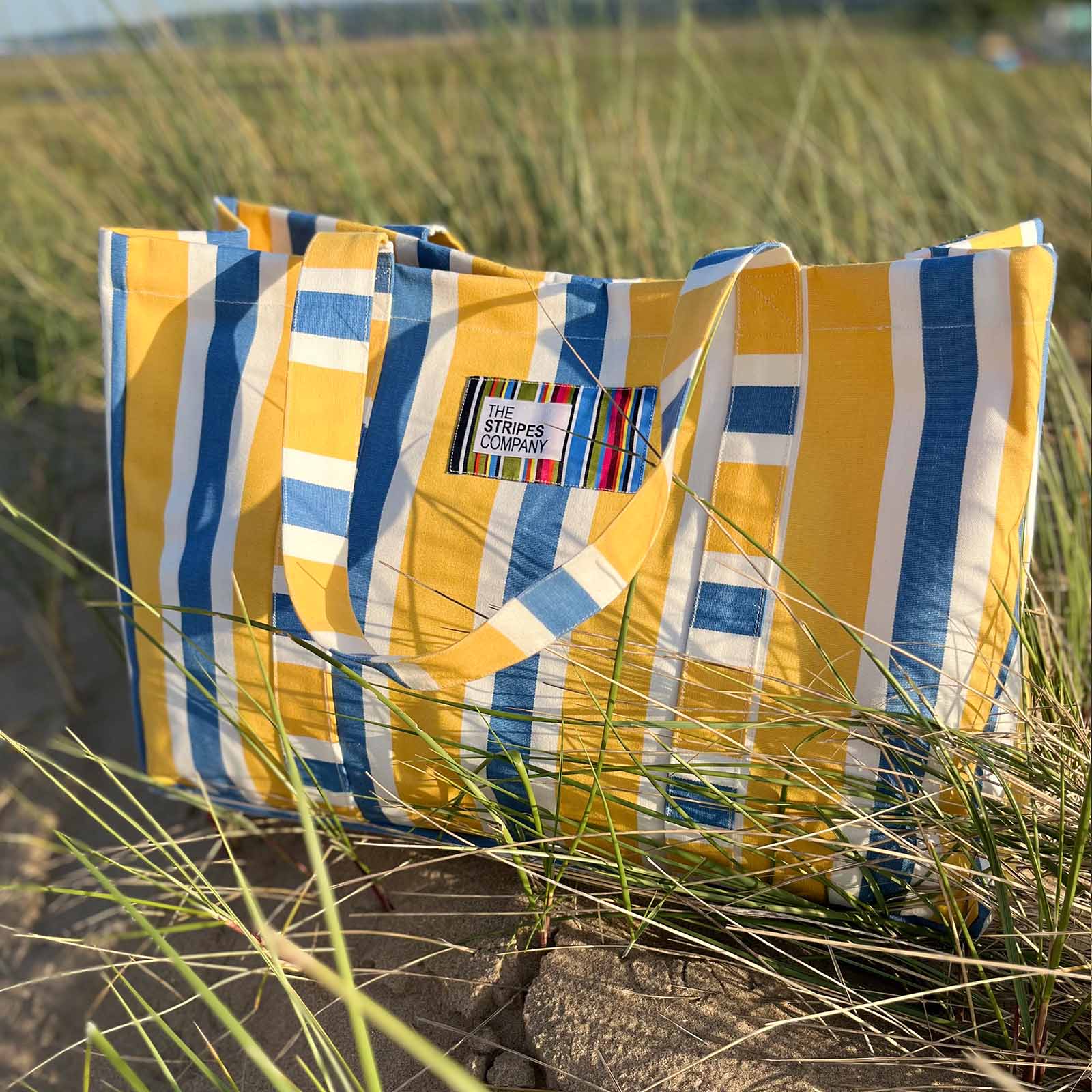 Yellow, blue, and white striped bag on a beach.