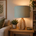 dark green and white striped drum lampshade styled in a cozy living room setting.
