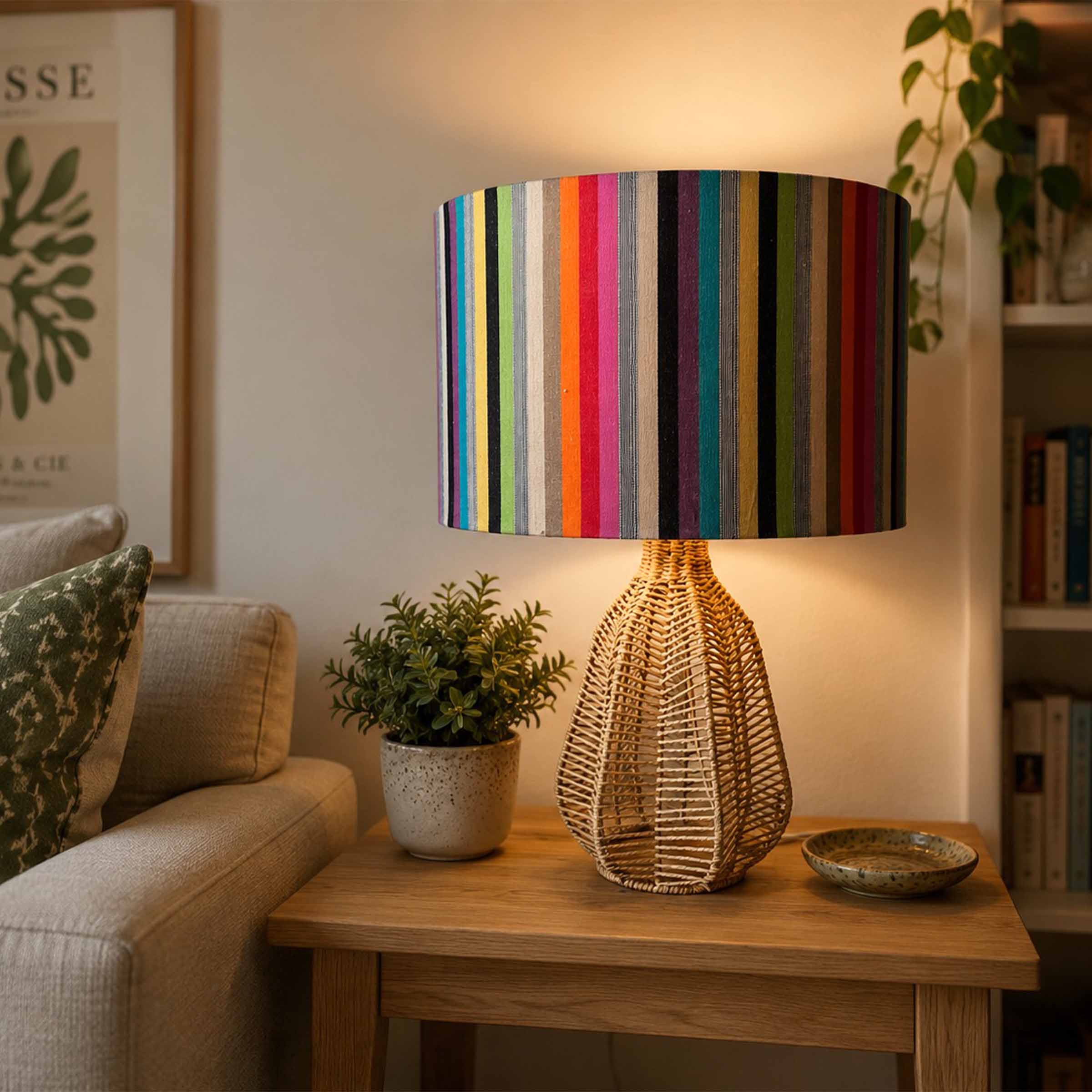 A table lamp with a colourful vertically striped fabric drum shade