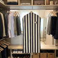 A navy and white striped suit garment cover on a hanger displayed inside a closet.