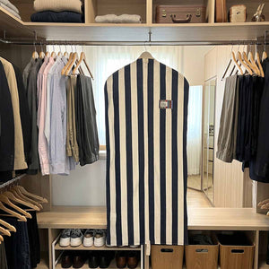 A navy and white striped suit garment cover on a hanger displayed inside a closet.